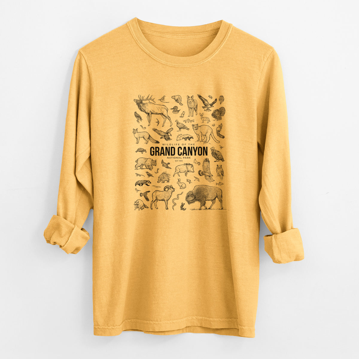 Golden wheat yellow Comfort Colors long sleeve shirt laid flat with the cuffs rolled, printed with a collection of black ink wildlife illustrations surrounding the words Grand Canyon National Park.