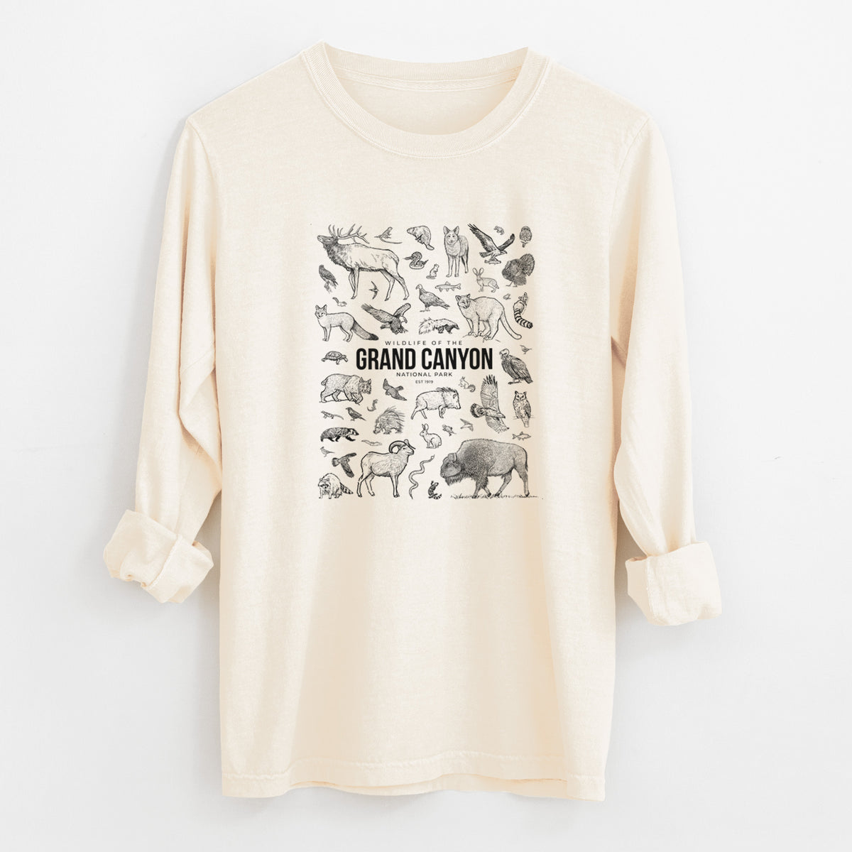 Ivory Comfort Colors long sleeve shirt laid flat with the cuffs rolled, printed with a collection of black ink wildlife illustrations surrounding the words Grand Canyon National Park.