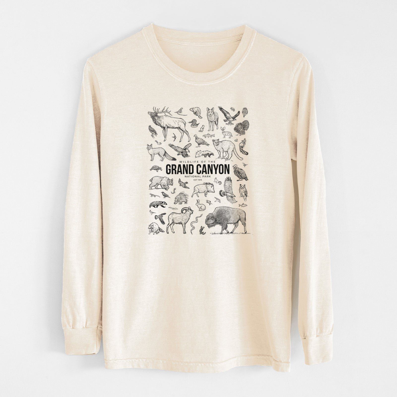 Ivory Comfort Colors long sleeve shirt laid flat, printed with a collection of black ink wildlife illustrations surrounding the words Grand Canyon National Park.