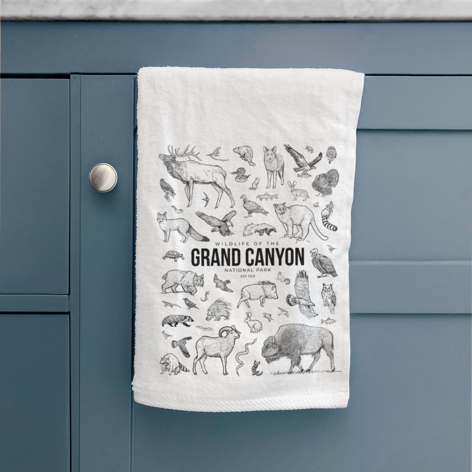 White hand towel printed with a collection of black ink wildlife illustrations surrounding the words Grand Canyon National Park.