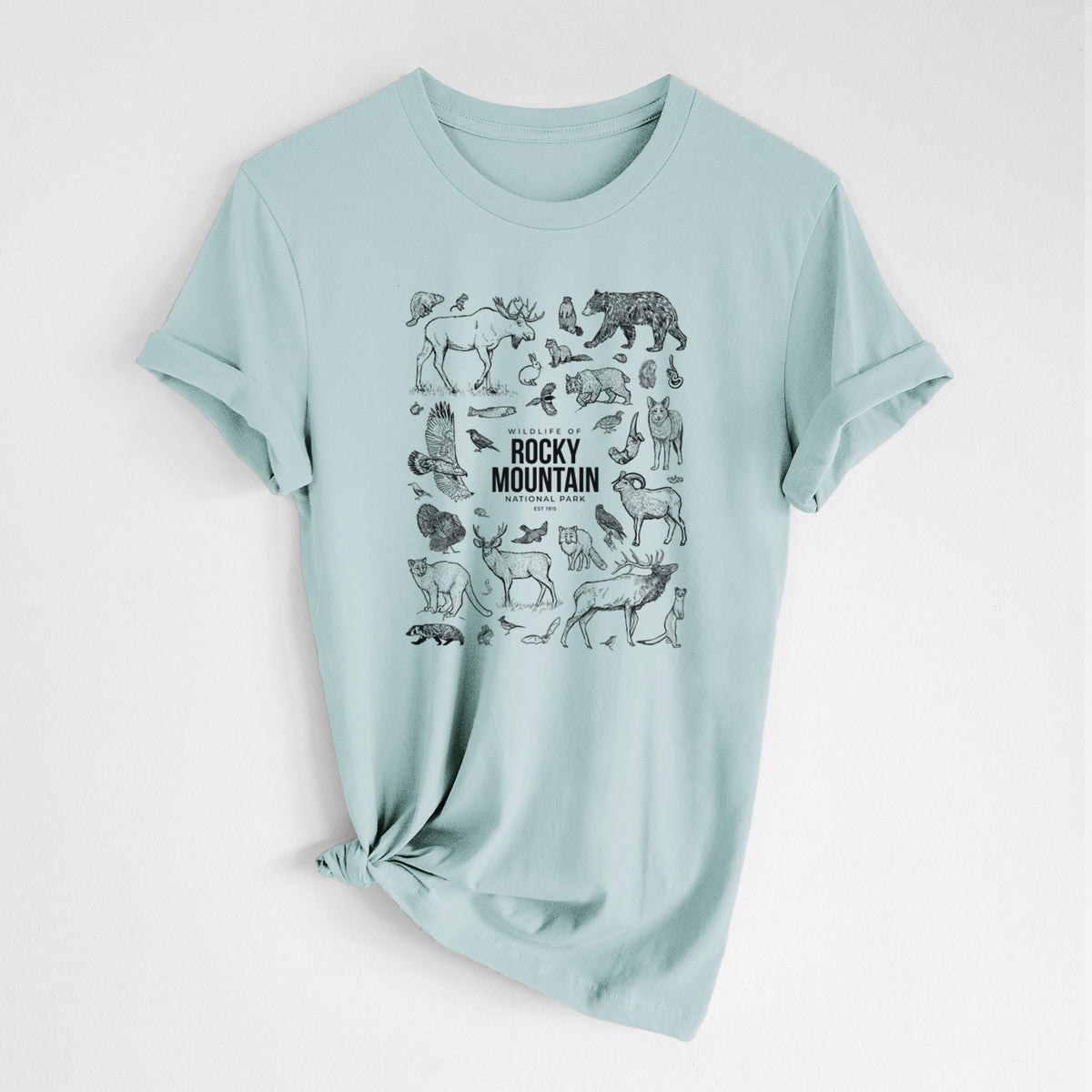 Dusty blue lightweight cotton t-shirt laid flat with the sleeves rolled, printed with a collection of black ink wildlife illustrations surrounding the words Rocky Mountain National Park.
