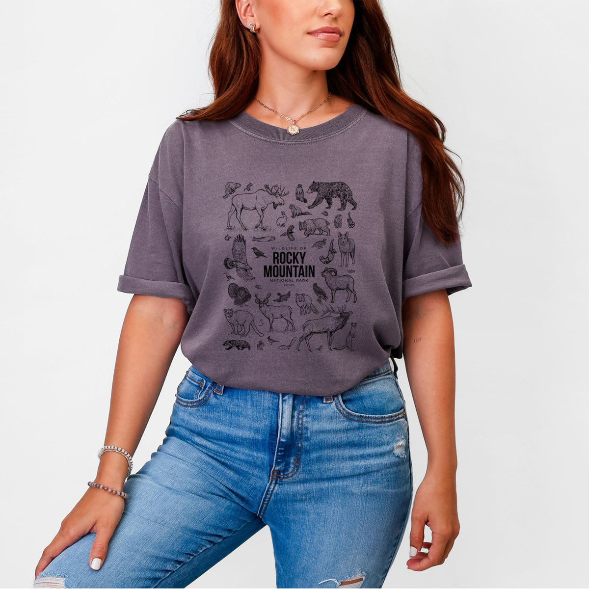 Woman wearing a Comfort Colors t-shirt printed with a collection of black ink wildlife illustrations surrounding the words Rocky Mountain National Park.