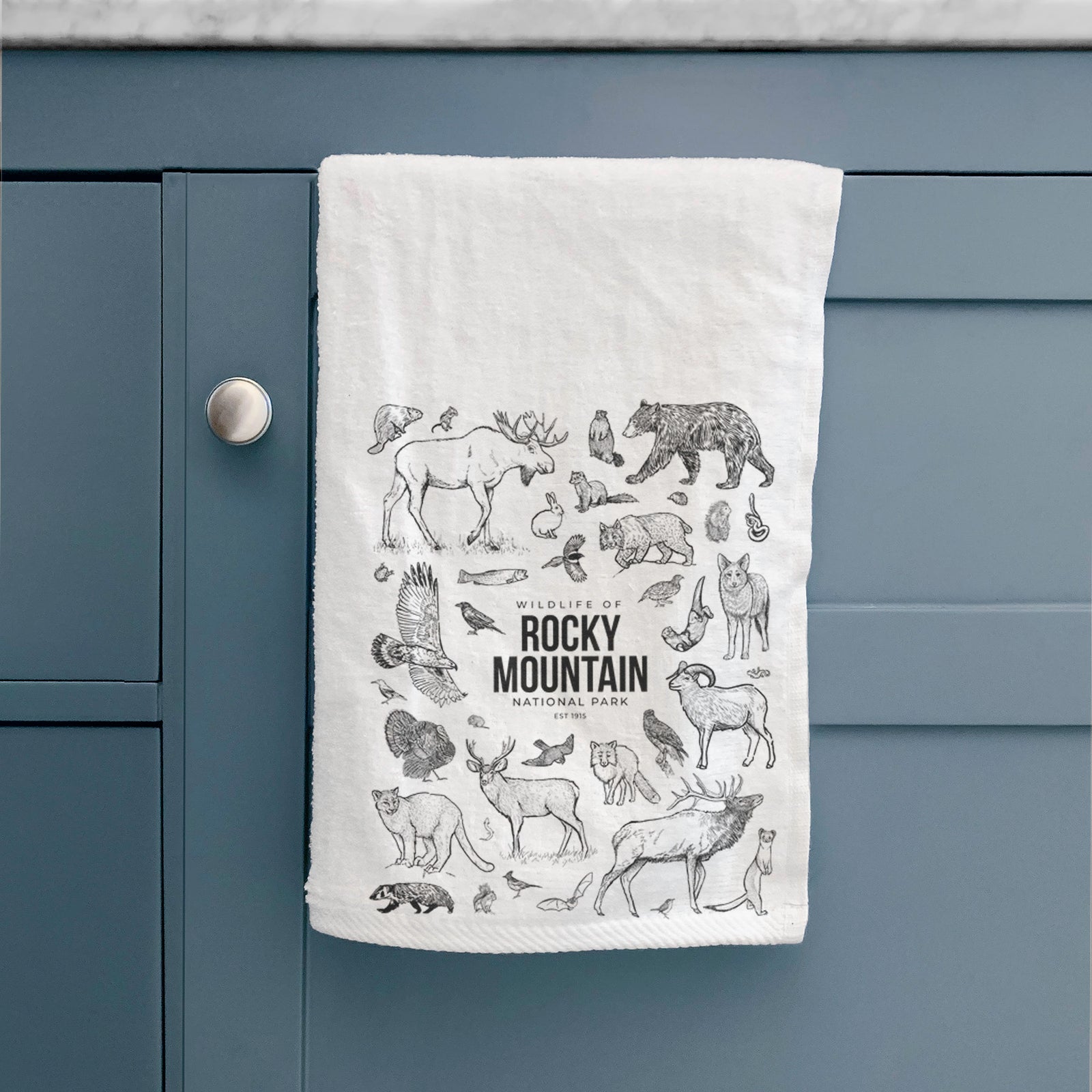 White hand towel printed with a collection of black ink wildlife illustrations surrounding the words Rocky Mountain National Park.