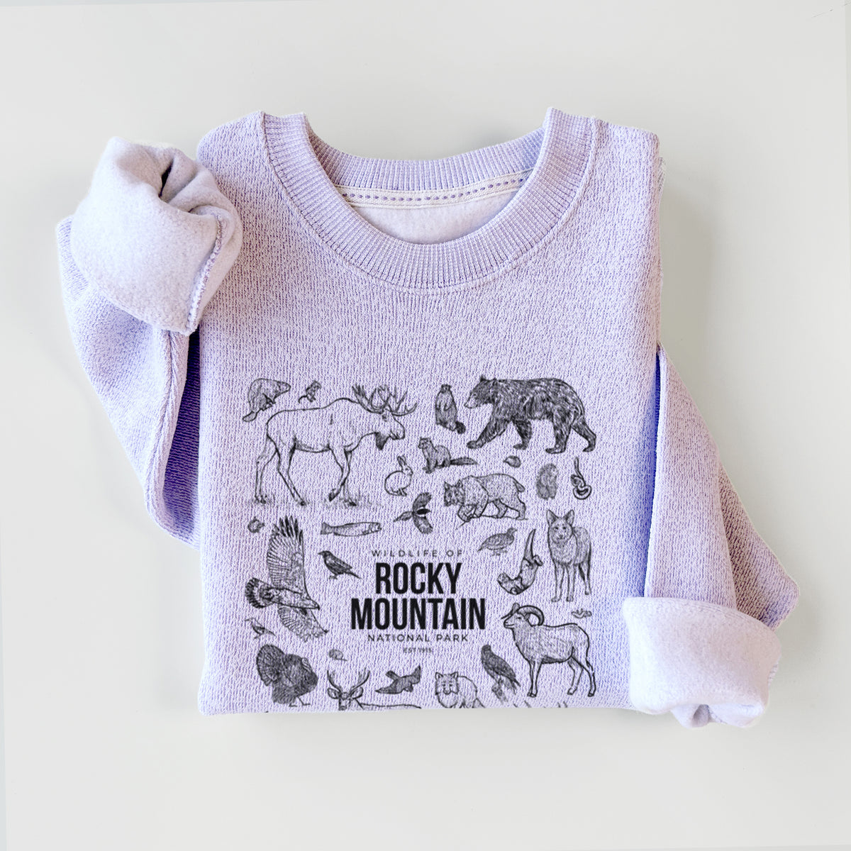 Ice purple knit sweatshirt printed with a collection of black ink wildlife illustrations surrounding the words Rocky Mountain National Park, styled flat.