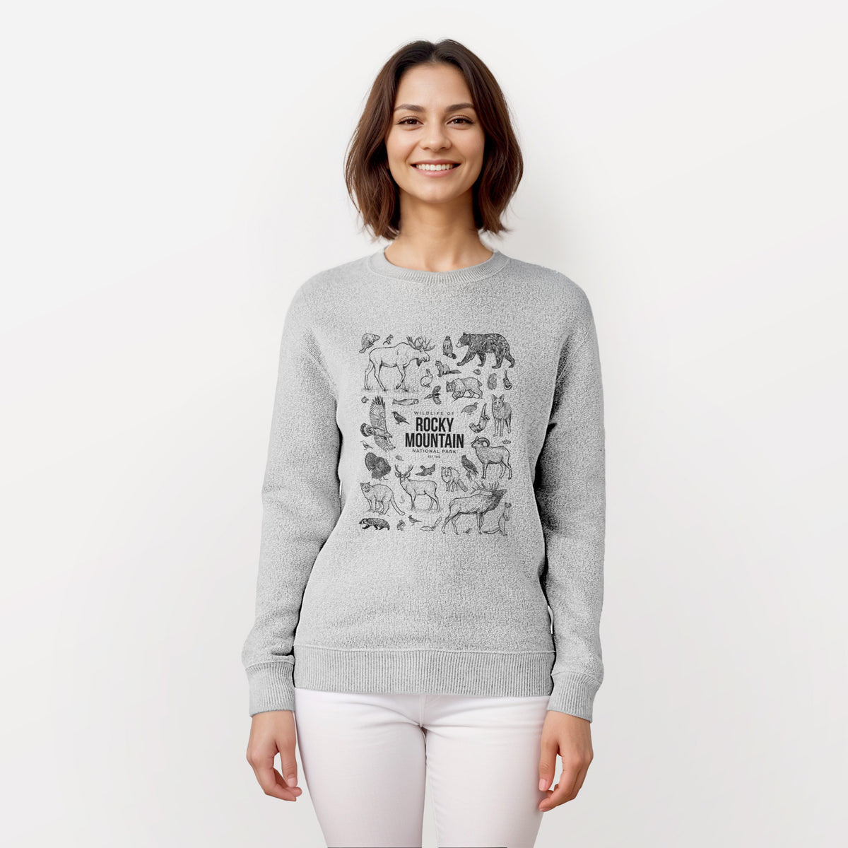 Woman wearing a knit sweatshirt printed with a collection of black ink wildlife illustrations surrounding the words Rocky Mountain National Park.
