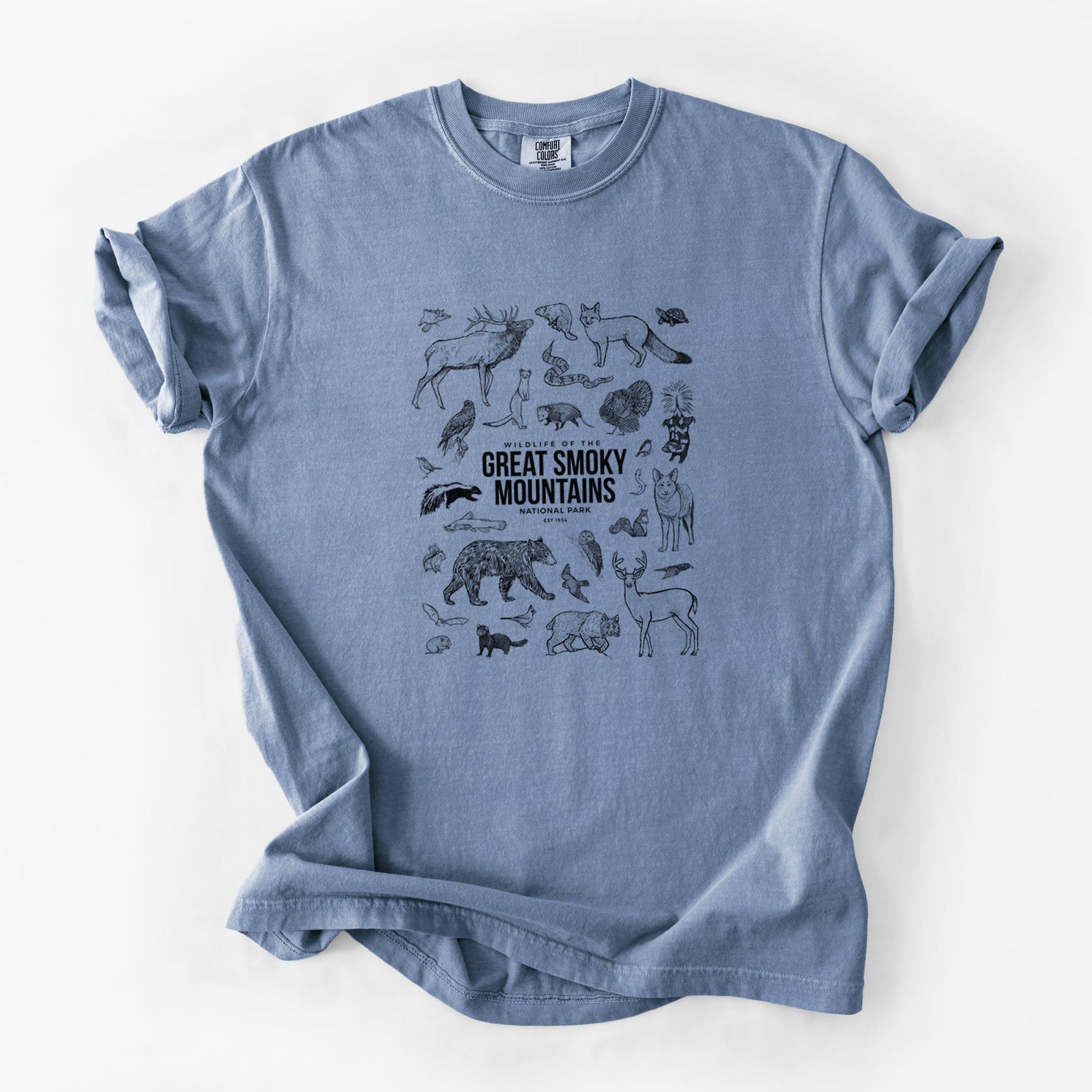Blue jean Comfort Colors t-shirt laid flat, printed with a collection of black ink wildlife illustrations surrounding the words Great Smoky Mountains National Park.