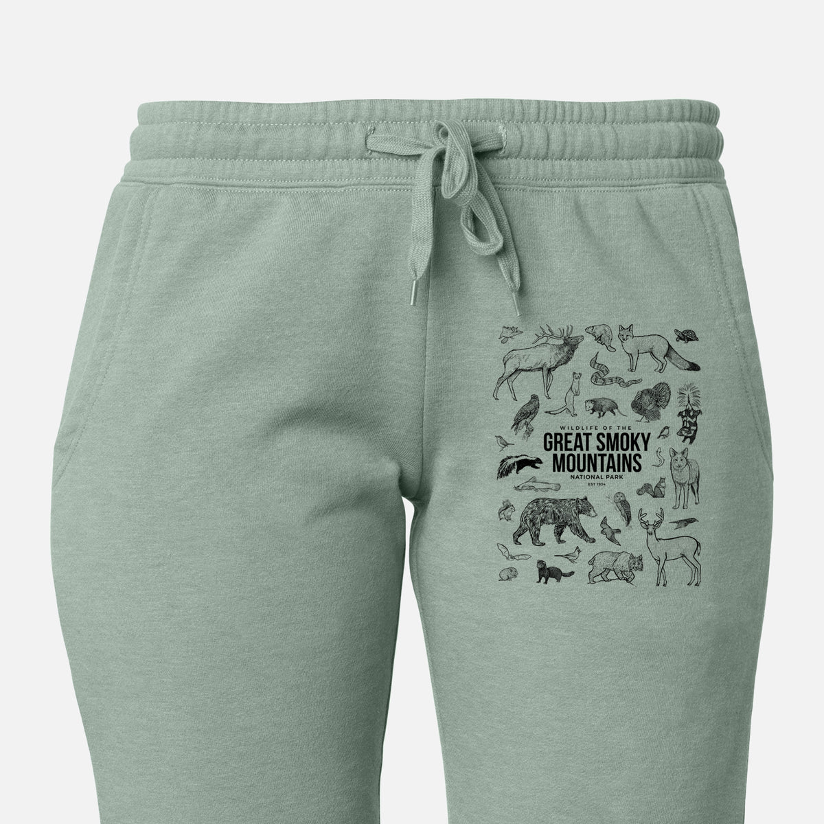 Front of sage green Cali Wave sweatpants, printed with a collection of black ink wildlife illustrations surrounding the words Great Smoky Mountains National Park on the leg.