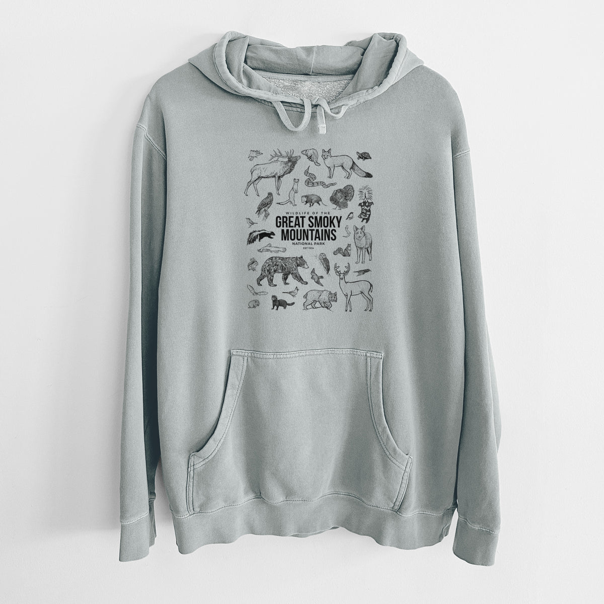 Sage green pigment dyed hoodie laid flat, printed with a collection of black ink wildlife illustrations surrounding the words Great Smoky Mountains National Park.