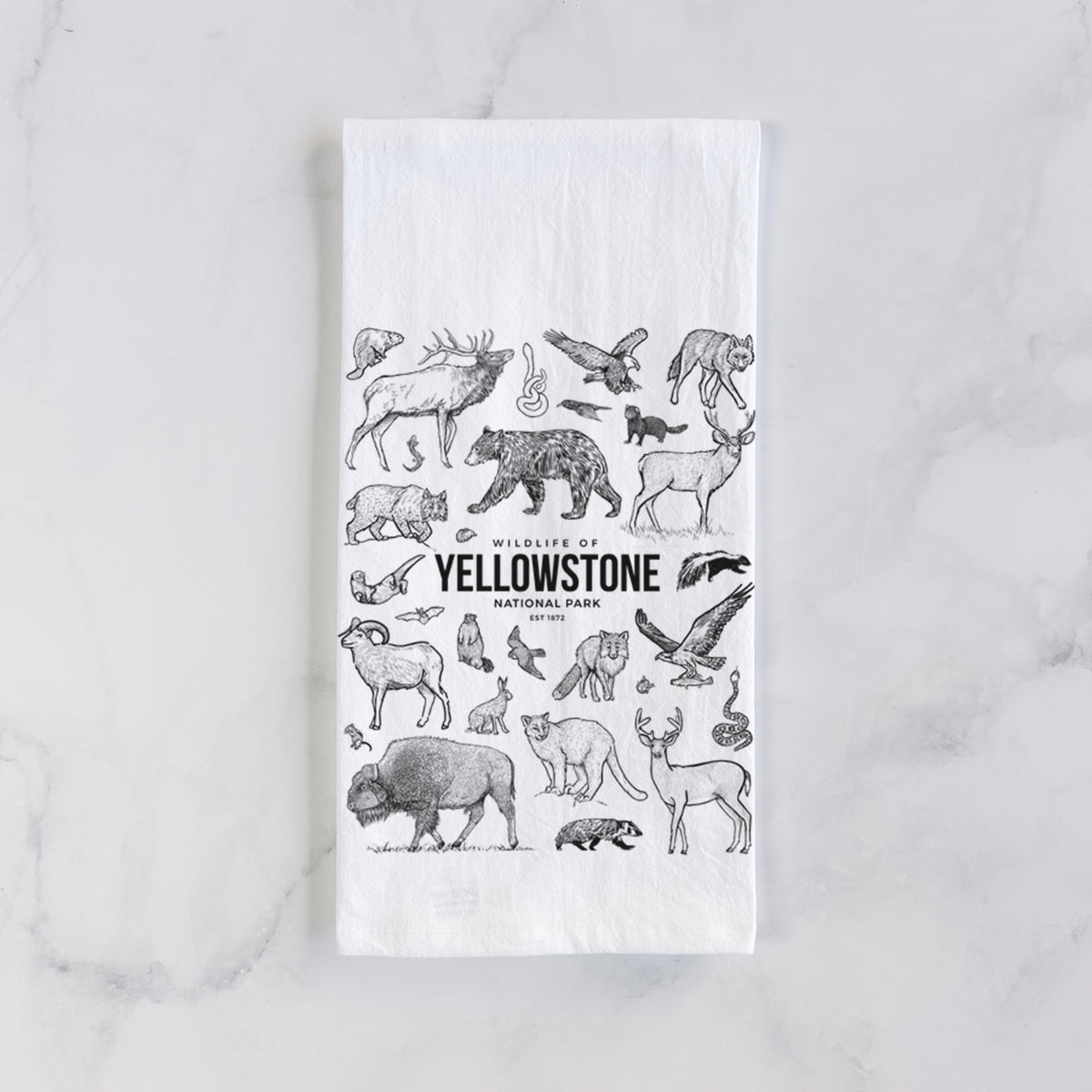 White cotton tea towel laid flat on marble, printed with a collection of black ink wildlife illustrations surrounding the words Yellowstone National Park.