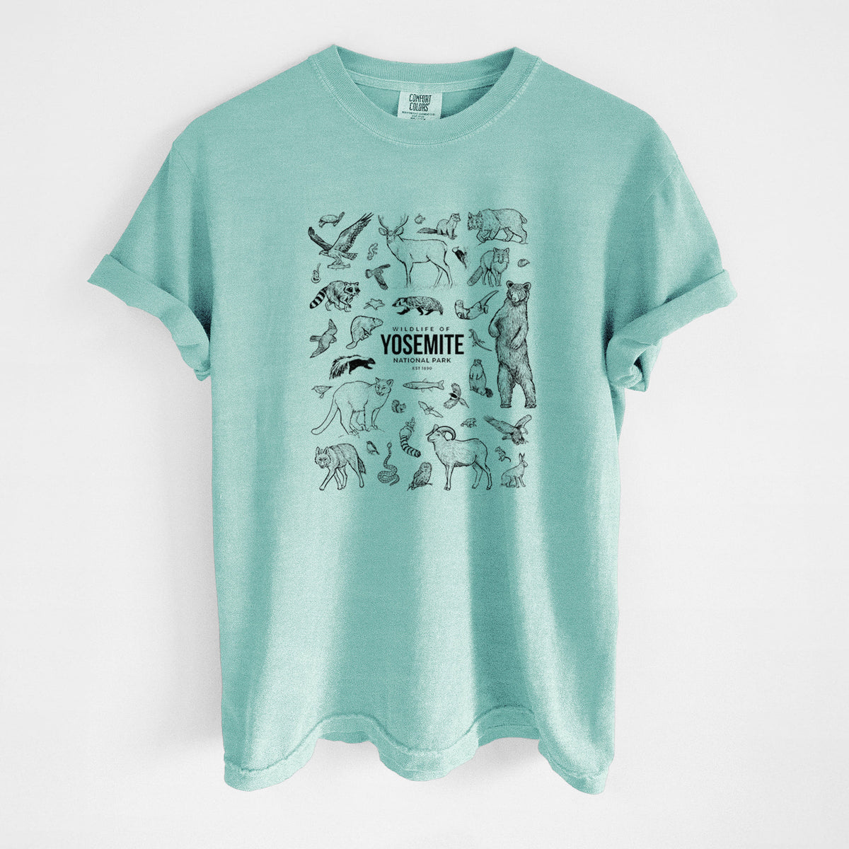 Chalky mint Comfort Colors t-shirt laid flat, printed with a collection of black ink wildlife illustrations surrounding the words Yosemite National Park.