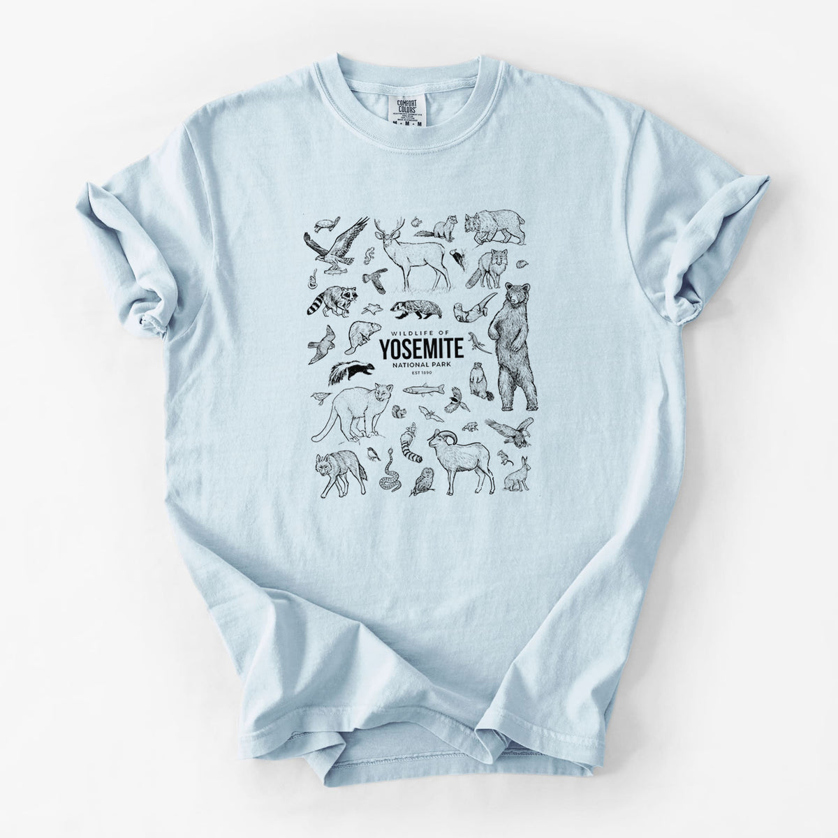 Chambray blue Comfort Colors t-shirt laid flat, printed with a collection of black ink wildlife illustrations surrounding the words Yosemite National Park.