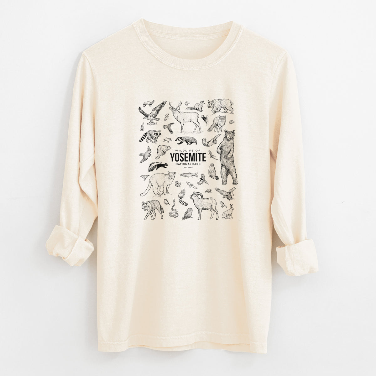 Ivory Comfort Colors long sleeve shirt laid flat with the cuffs rolled, printed with a collection of black ink wildlife illustrations surrounding the words Yosemite National Park.