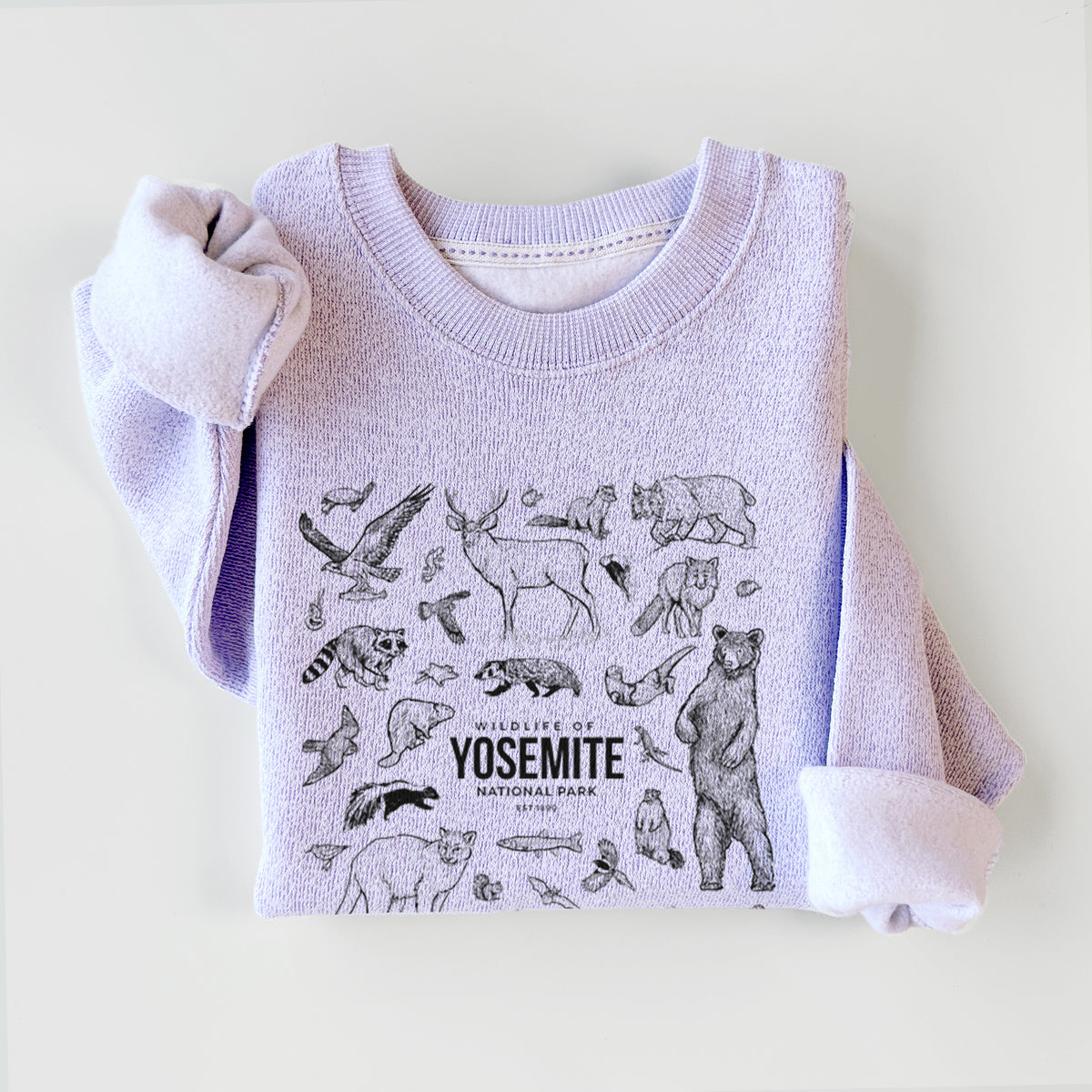 Ice purple knit sweatshirt printed with a collection of black ink wildlife illustrations surrounding the words Yosemite National Park, styled flat.