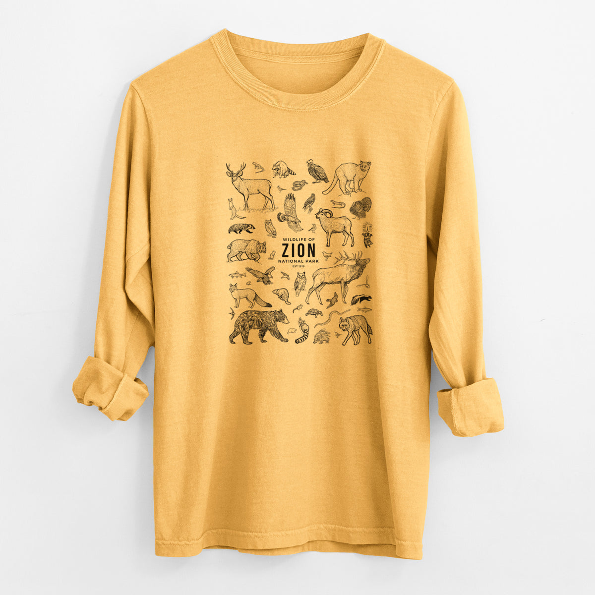 Golden wheat yellow Comfort Colors long sleeve shirt laid flat with the cuffs rolled, printed with a collection of black ink wildlife illustrations surrounding the words Zion National Park.