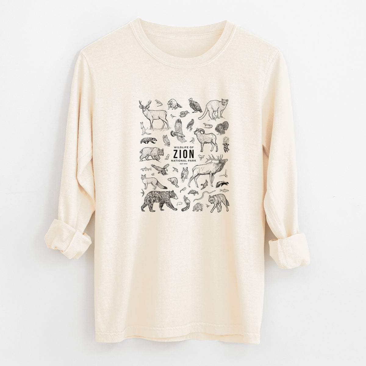 Ivory Comfort Colors long sleeve shirt laid flat with the cuffs rolled, printed with a collection of black ink wildlife illustrations surrounding the words Zion National Park.
