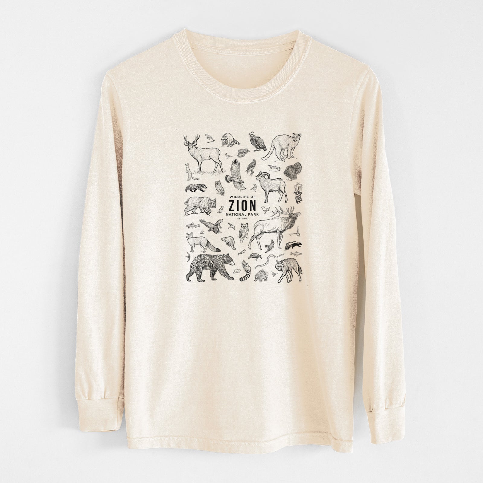 Ivory Comfort Colors long sleeve shirt laid flat, printed with a collection of black ink wildlife illustrations surrounding the words Zion National Park.