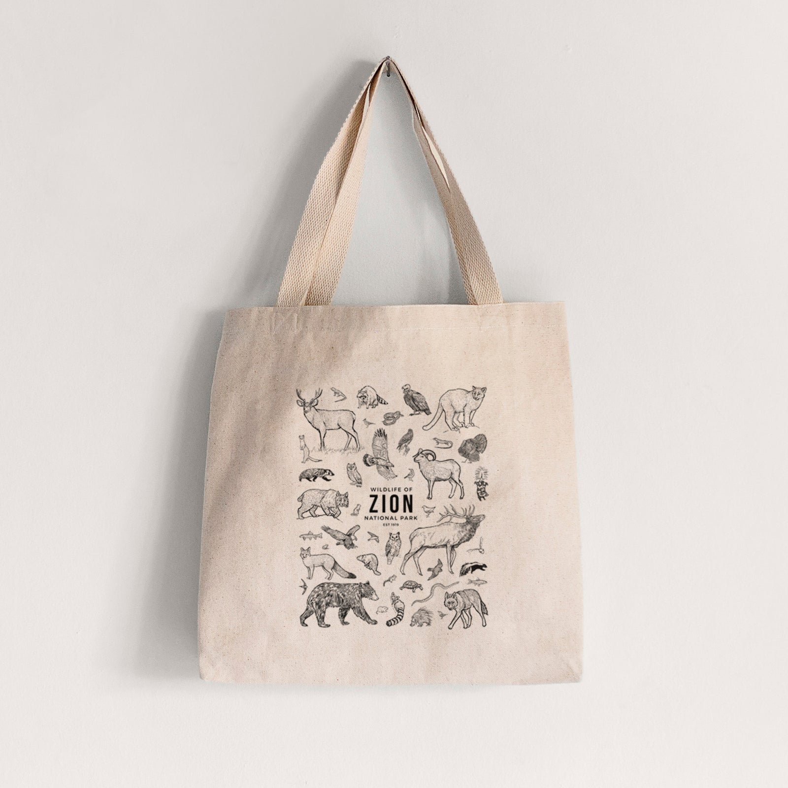 Natural canvas tote bag printed with a collection of black ink wildlife illustrations surrounding the words Zion National Park.