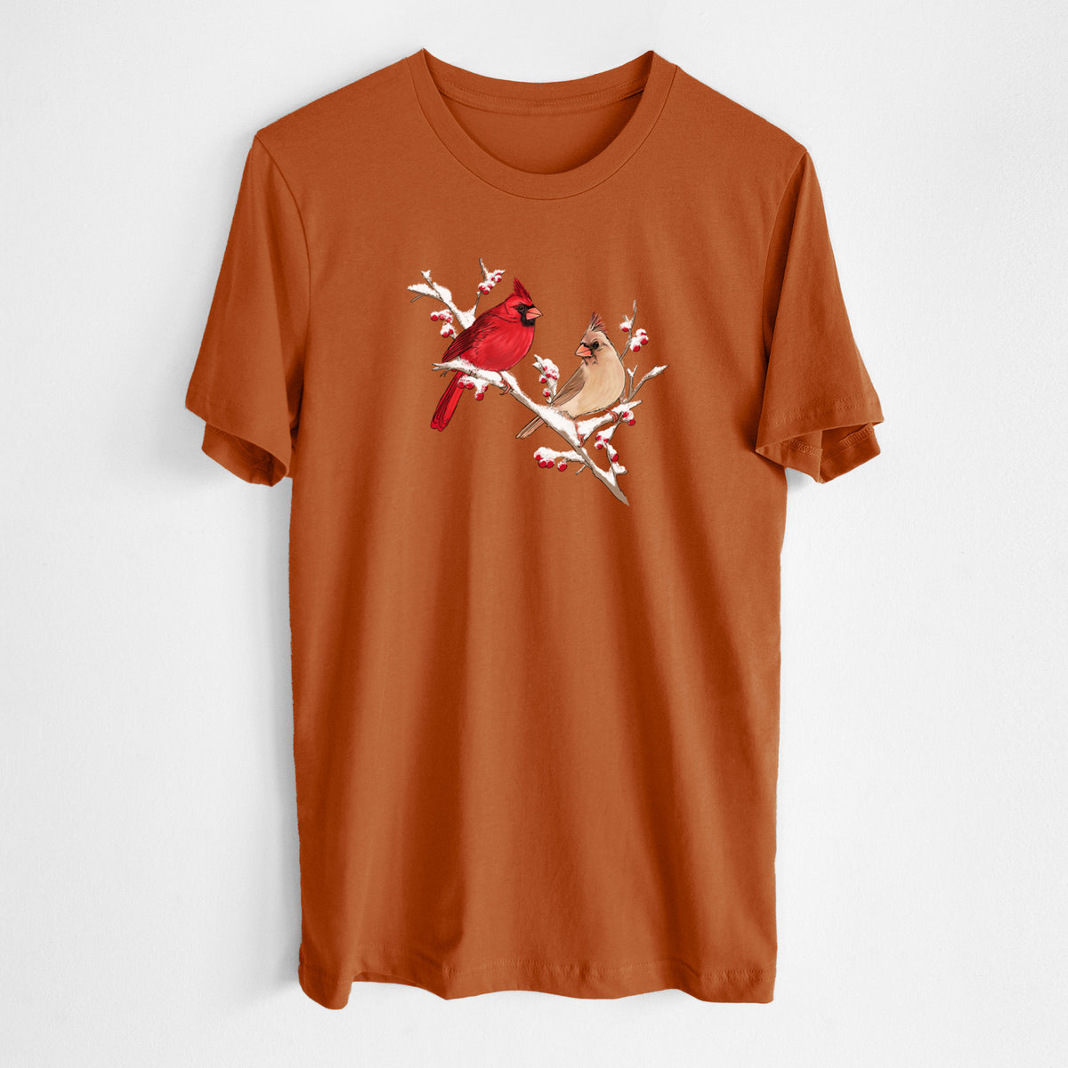 Autumn lightweight cotton t-shirt laid flat, printed with a full-color illustration of a male and female northern cardinal perched on a snowy branch with red berries.