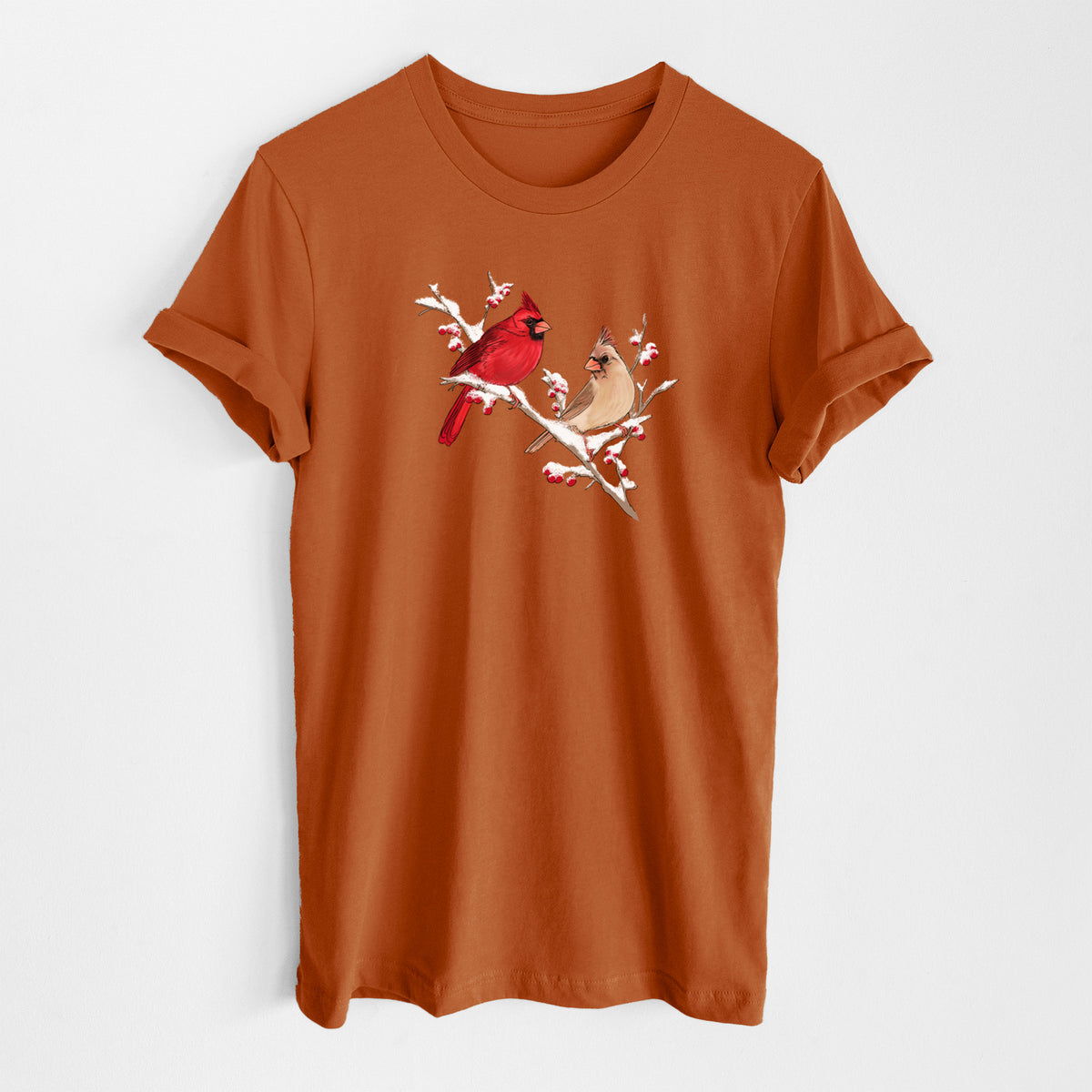 Autumn lightweight cotton t-shirt laid flat, printed with a full-color illustration of a male and female northern cardinal perched on a snowy branch with red berries.