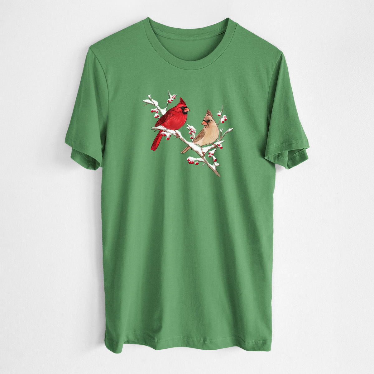Leaf green lightweight cotton t-shirt laid flat, printed with a full-color illustration of a male and female northern cardinal perched on a snowy branch with red berries.