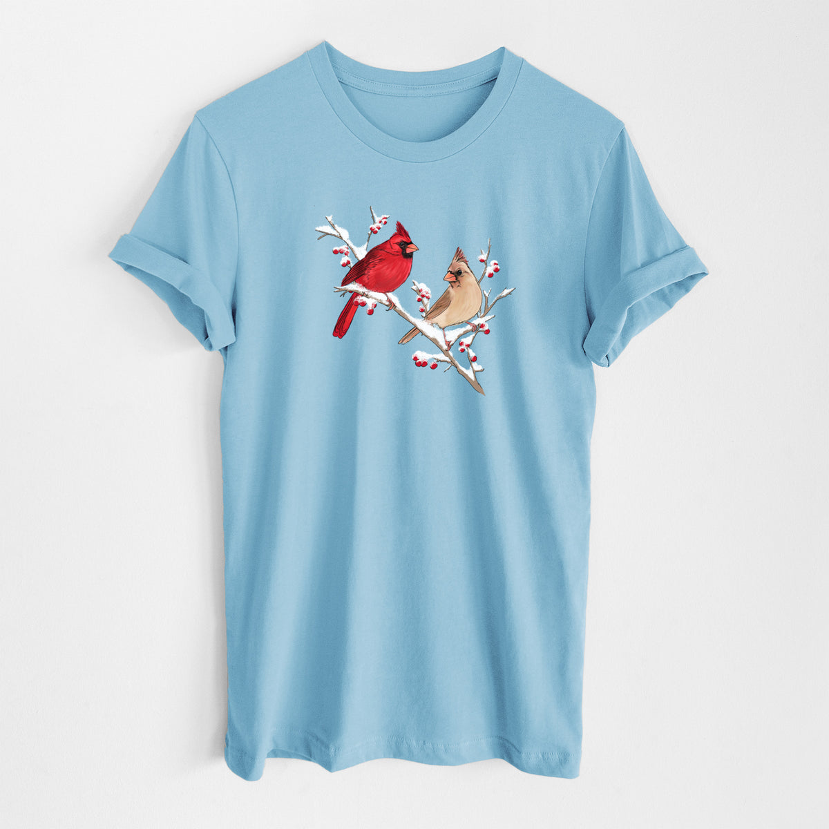 Ocean blue lightweight cotton t-shirt laid flat, printed with a full-color illustration of a male and female northern cardinal perched on a snowy branch with red berries.