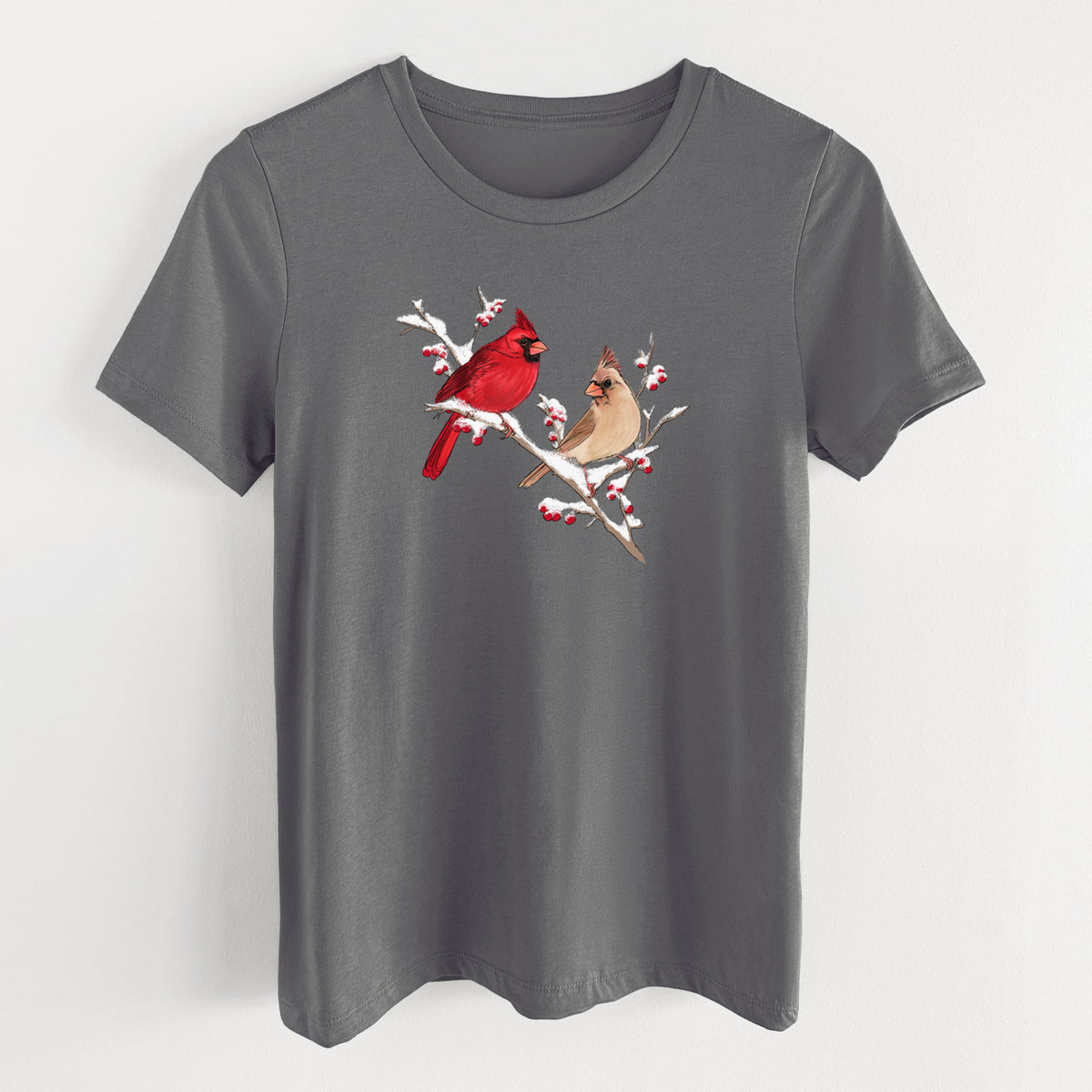 Asphalt women's relaxed fit cotton t-shirt laid flat, printed with a full-color illustration of a male and female northern cardinal perched on a snowy branch with red berries.