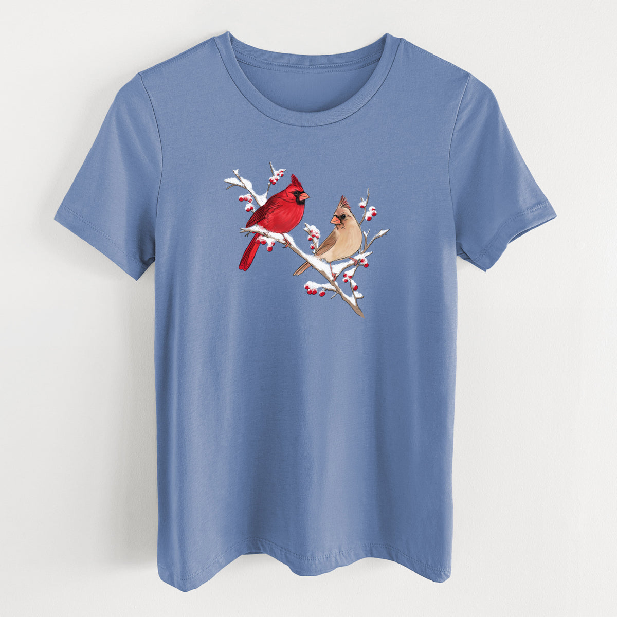 Blue bell women's relaxed fit cotton t-shirt laid flat, printed with a full-color illustration of a male and female northern cardinal perched on a snowy branch with red berries.