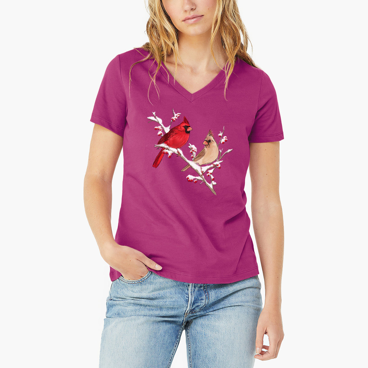 Woman wearing a berry pink women's relaxed fit cotton V-neck t-shirt printed with a full-color illustration of a male and female northern cardinal perched on a snowy branch with red berries.