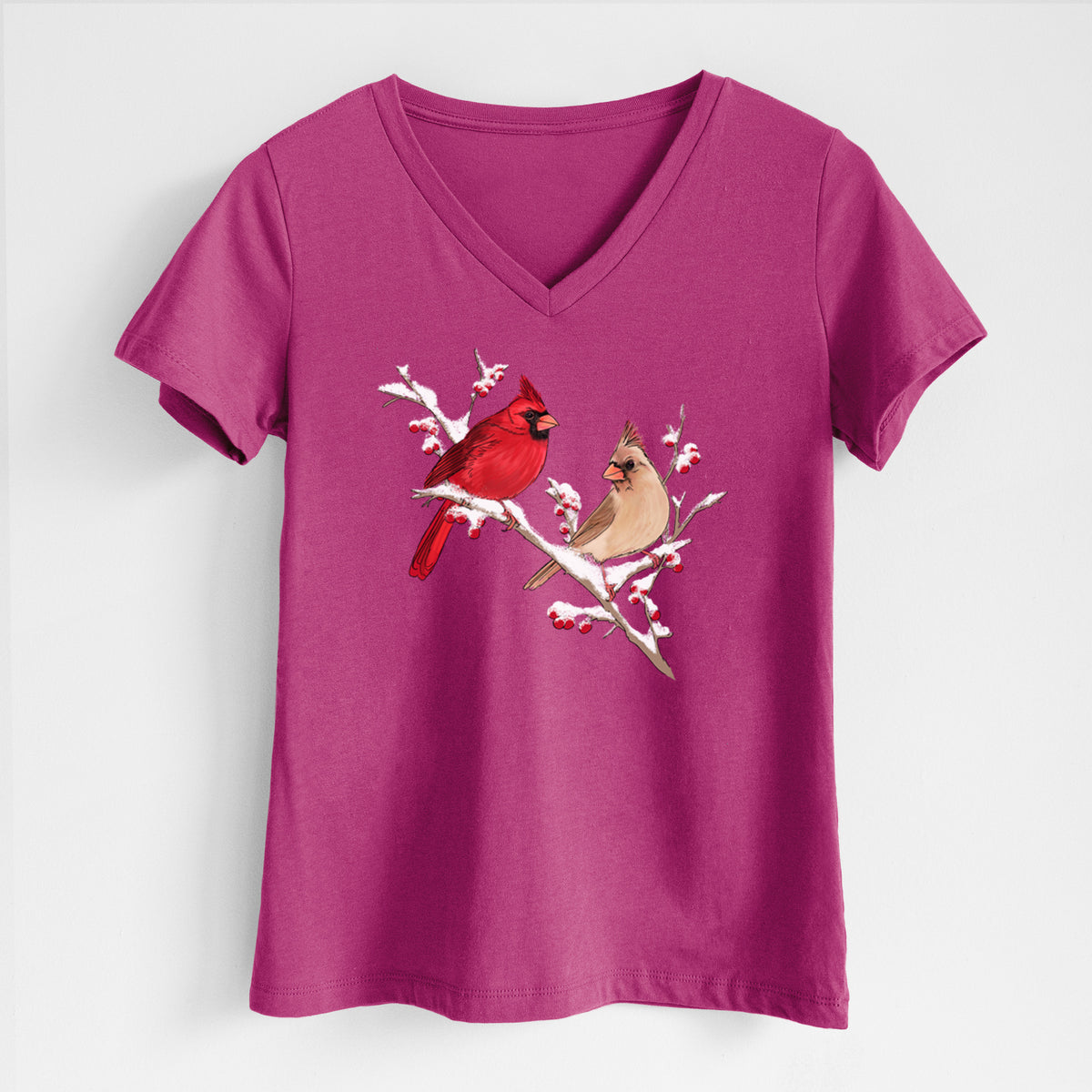 Berry pink women's relaxed fit cotton V-neck t-shirt laid flat, printed with a full-color illustration of a male and female northern cardinal perched on a snowy branch with red berries.