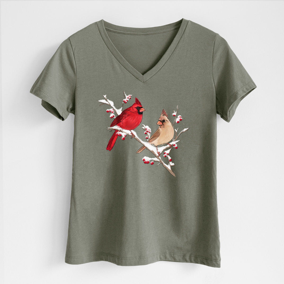 Military green women's relaxed fit cotton V-neck t-shirt laid flat, printed with a full-color illustration of a male and female northern cardinal perched on a snowy branch with red berries.