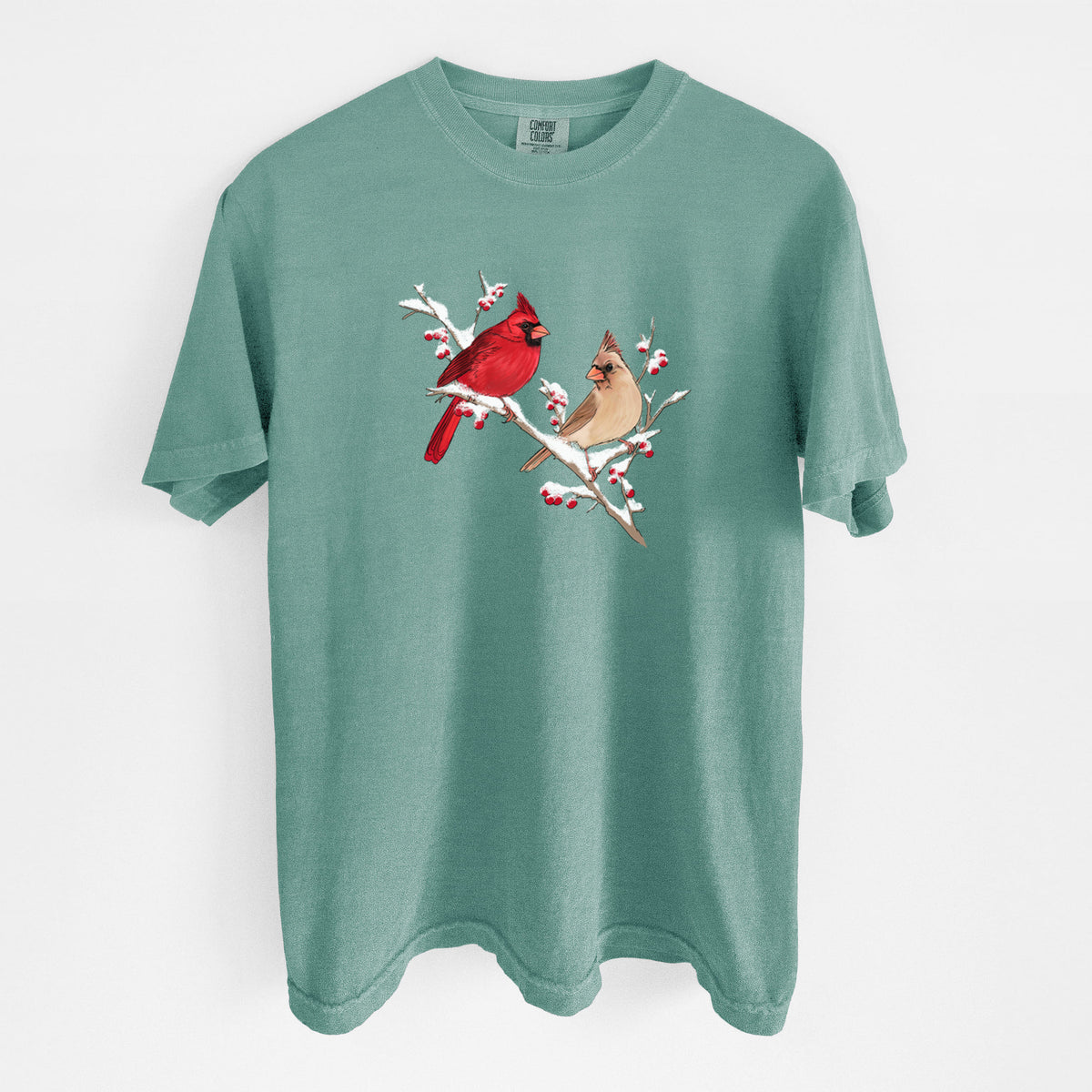 Reef green Comfort Colors t-shirt laid flat, printed with a full-color illustration of a male and female northern cardinal perched on a snowy branch with red berries.