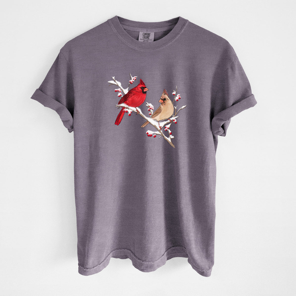 Wine red Comfort Colors t-shirt laid flat, printed with a full-color illustration of a male and female northern cardinal perched on a snowy branch with red berries.
