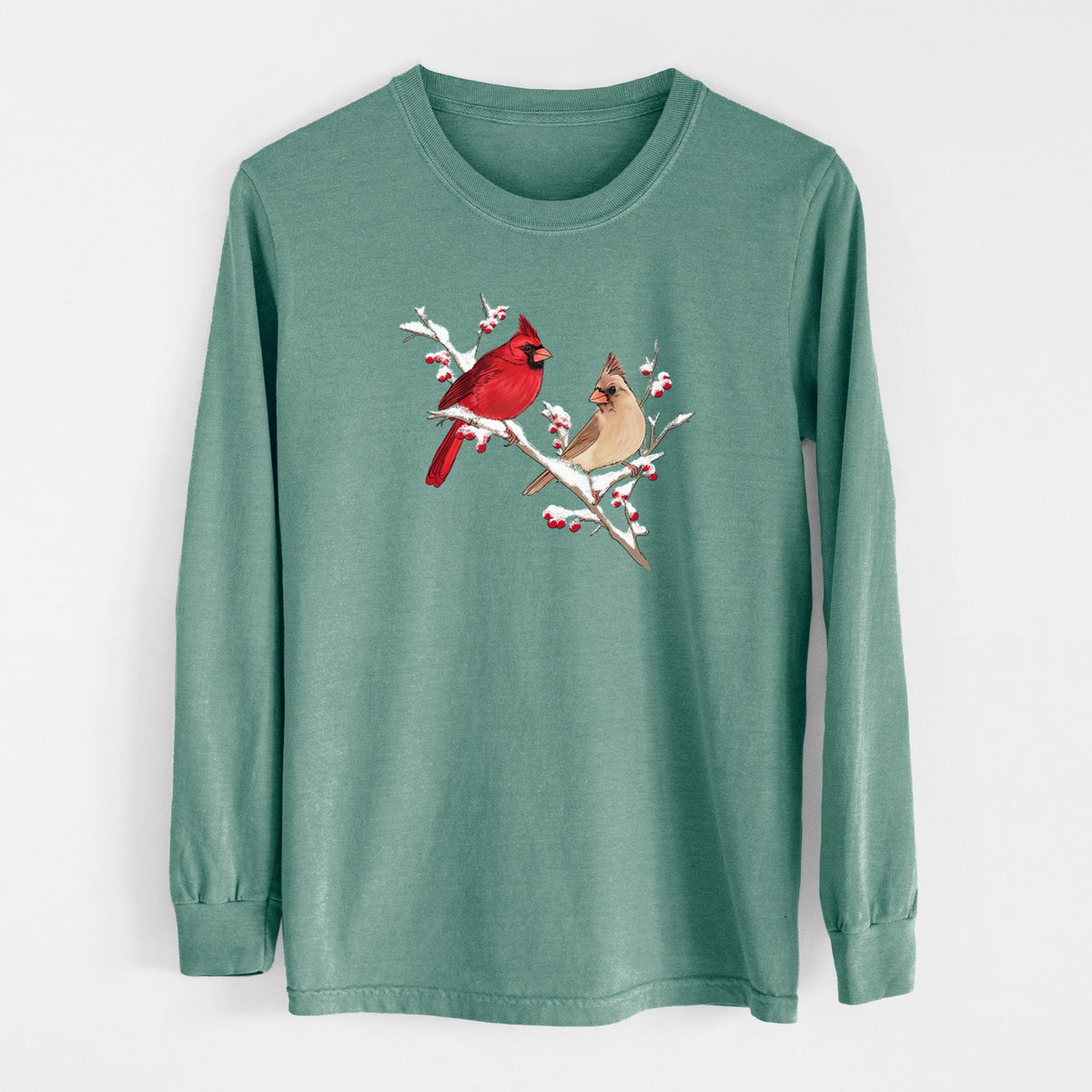 Pine green Comfort Colors long sleeve shirt laid flat, printed with a full-color illustration of a male and female northern cardinal perched on a snowy branch with red berries.