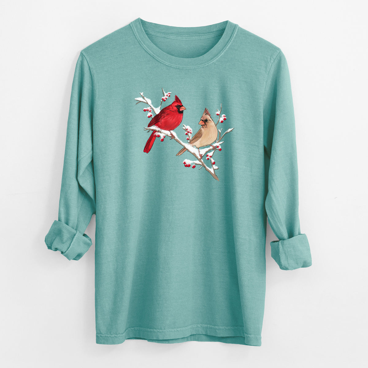 Reef green Comfort Colors long sleeve shirt laid flat with the cuffs rolled, printed with a full-color illustration of a male and female northern cardinal perched on a snowy branch with red berries.