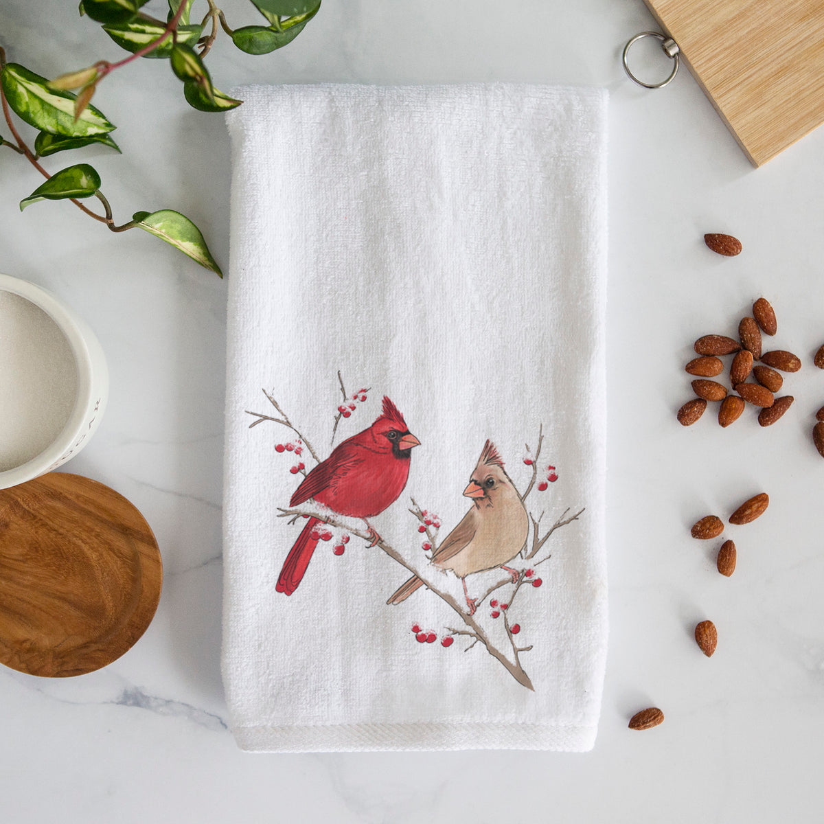 White hand towel printed with a full-color illustration of a male and female northern cardinal perched on a snowy branch with red berries.