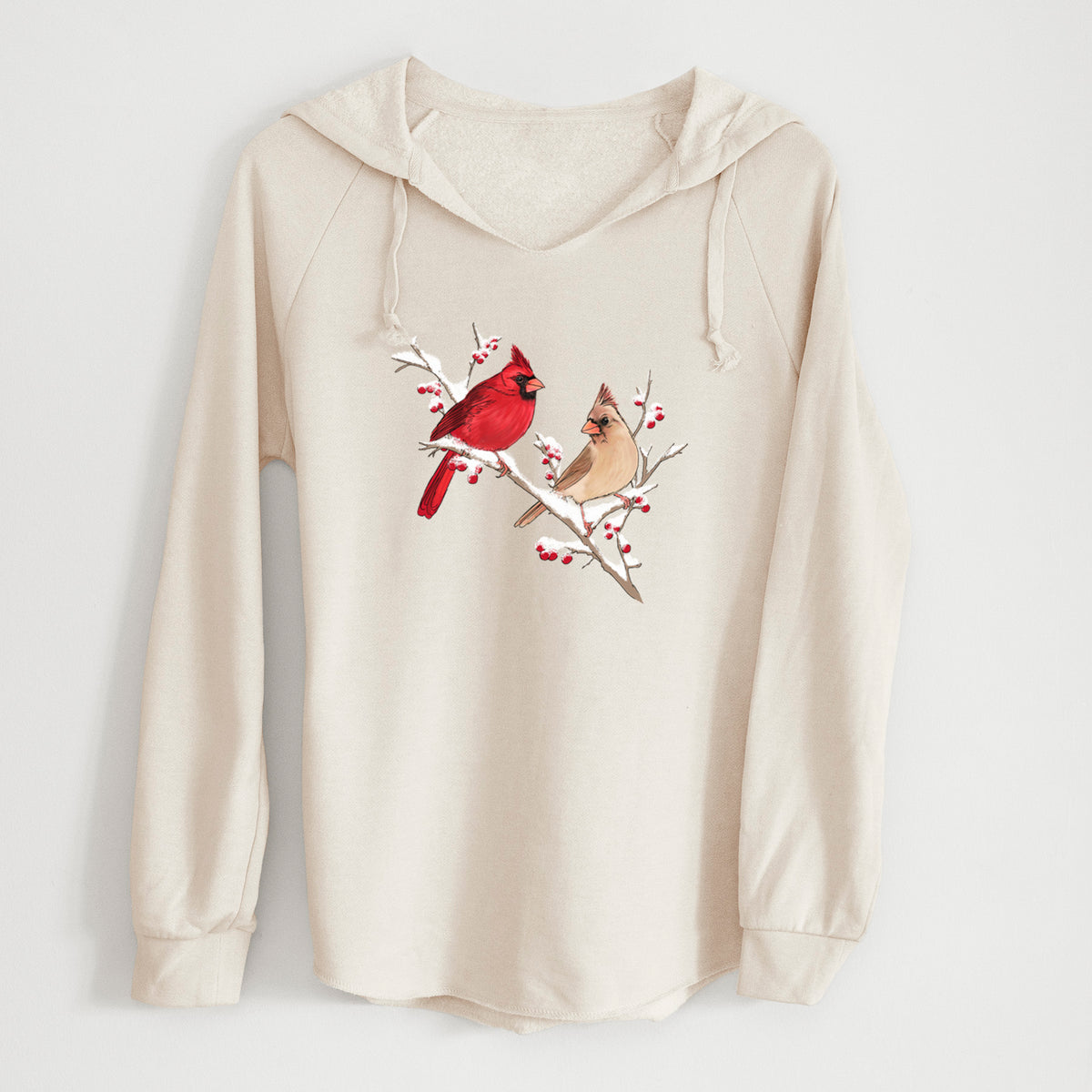 Bone cream women's Cali Wave hooded sweatshirt laid flat, printed with a full-color illustration of a male and female northern cardinal perched on a snowy branch with red berries.