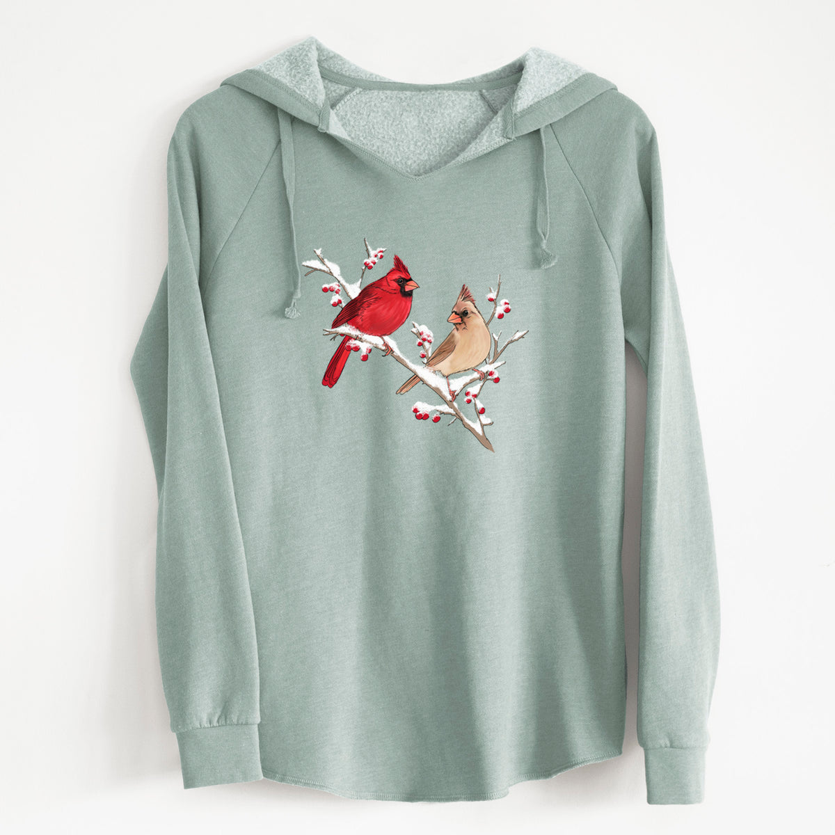 Sage green women's Cali Wave hooded sweatshirt laid flat, printed with a full-color illustration of a male and female northern cardinal perched on a snowy branch with red berries.
