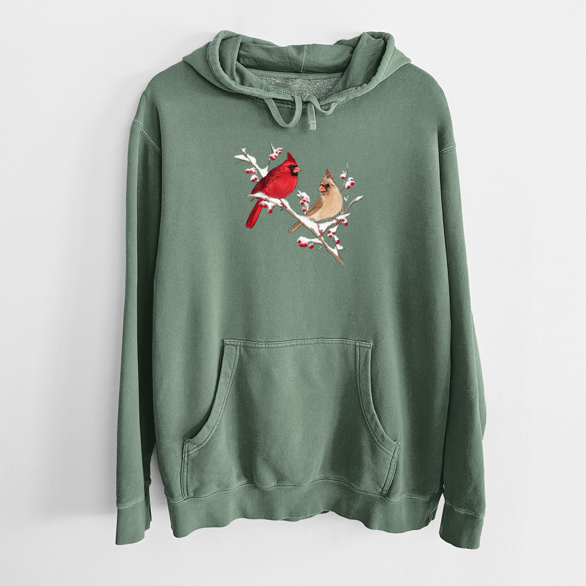 Alpine green pigment dyed hoodie laid flat, printed with a full-color illustration of a male and female northern cardinal perched on a snowy branch with red berries.