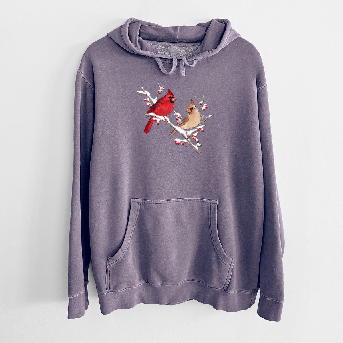 Plum purple pigment dyed hoodie laid flat, printed with a full-color illustration of a male and female northern cardinal perched on a snowy branch with red berries.