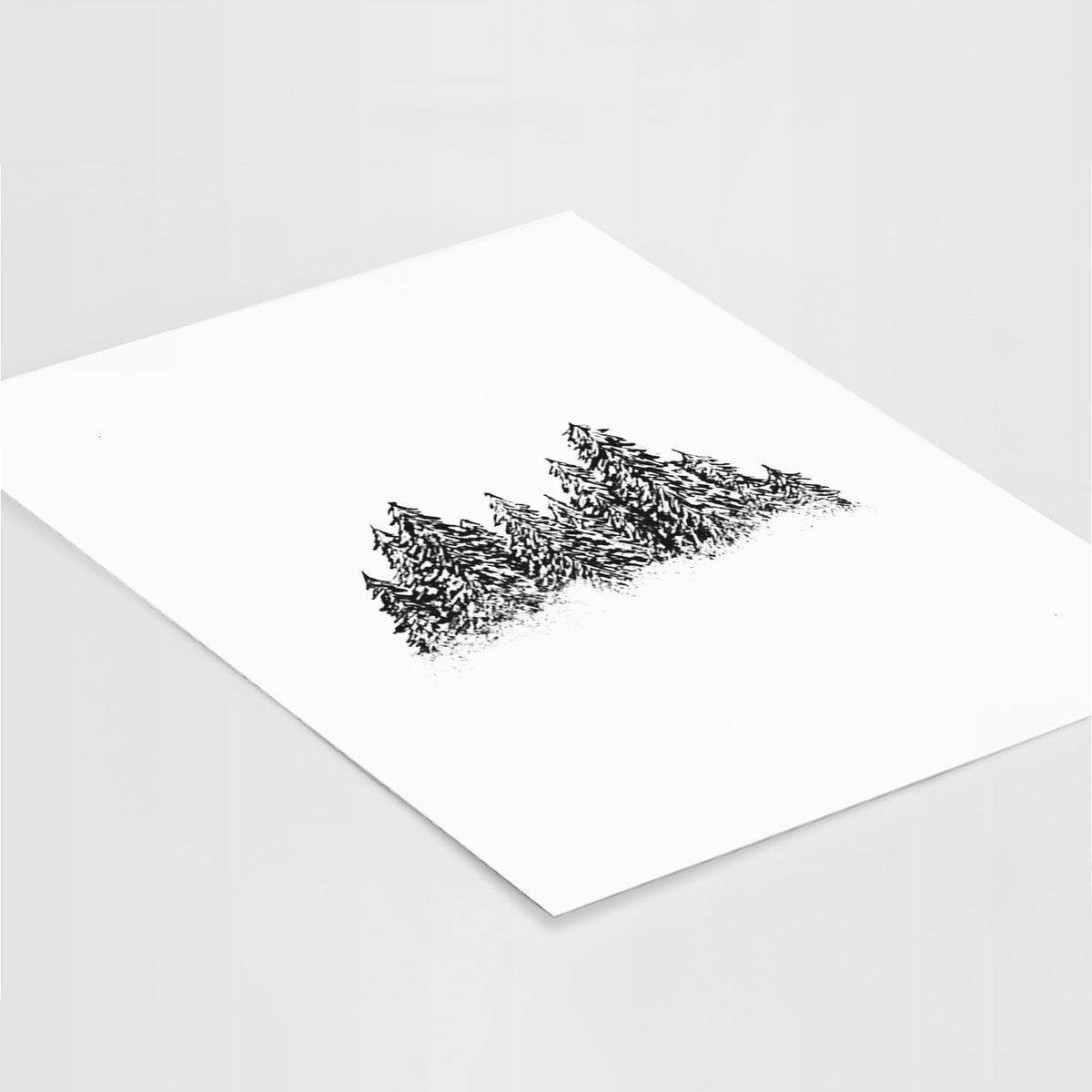 Art print of a black ink illustration of a row of snow-dusted evergreen trees, lying at an angle on a white surface.