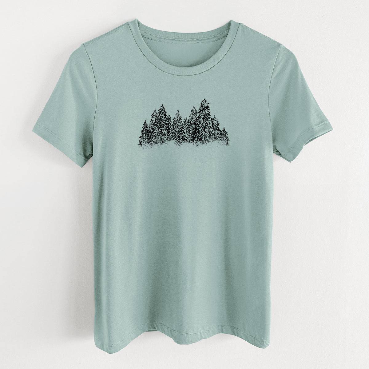 Dusty blue women's relaxed fit cotton t-shirt laid flat, printed with a black ink illustration of a row of snow-dusted evergreen trees.