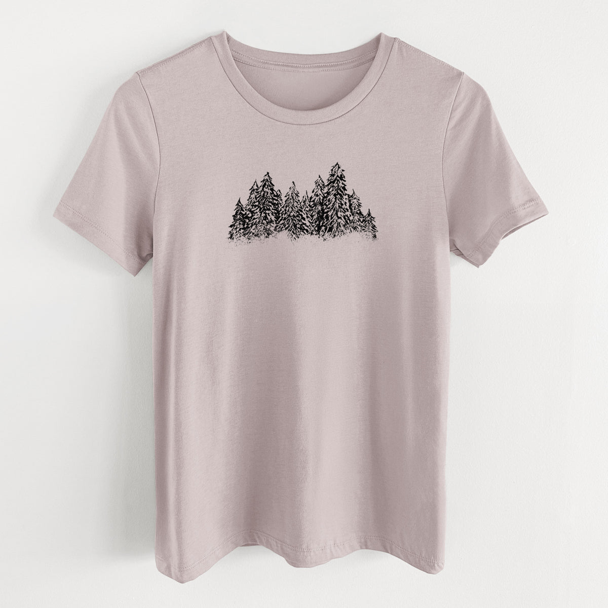 Pink gravel women's relaxed fit cotton t-shirt laid flat, printed with a black ink illustration of a row of snow-dusted evergreen trees.