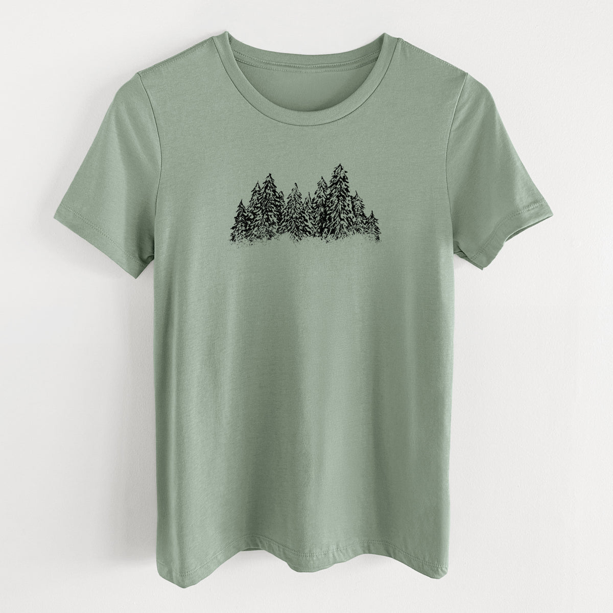 Sage green women's relaxed fit cotton t-shirt laid flat, printed with a black ink illustration of a row of snow-dusted evergreen trees.