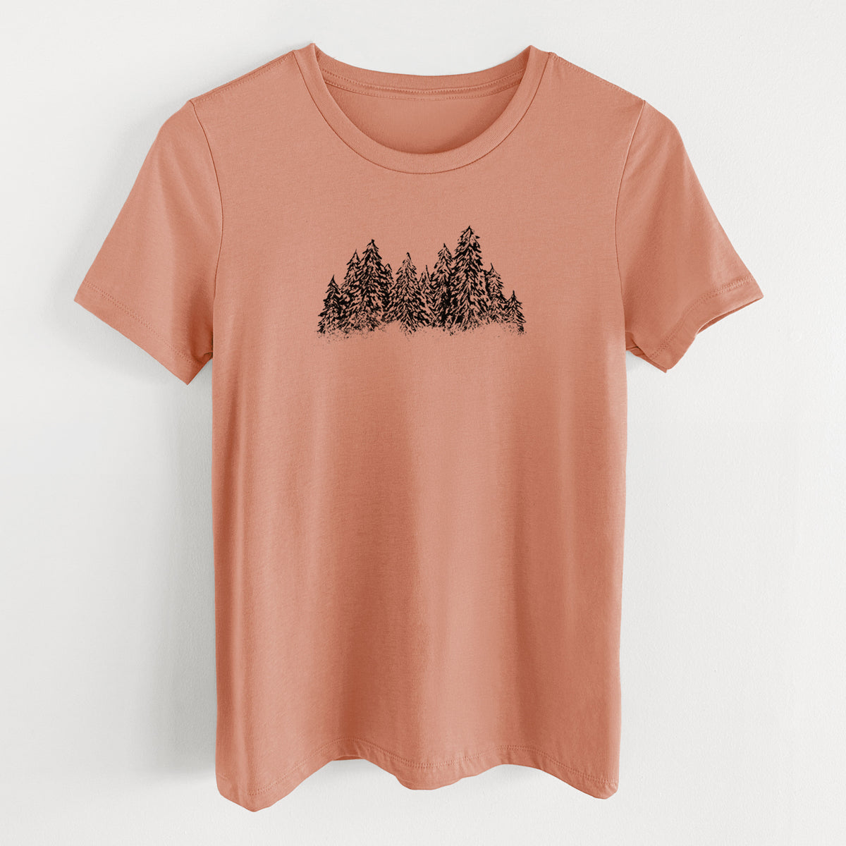 Terracotta orange women's relaxed fit cotton t-shirt laid flat, printed with a black ink illustration of a row of snow-dusted evergreen trees.
