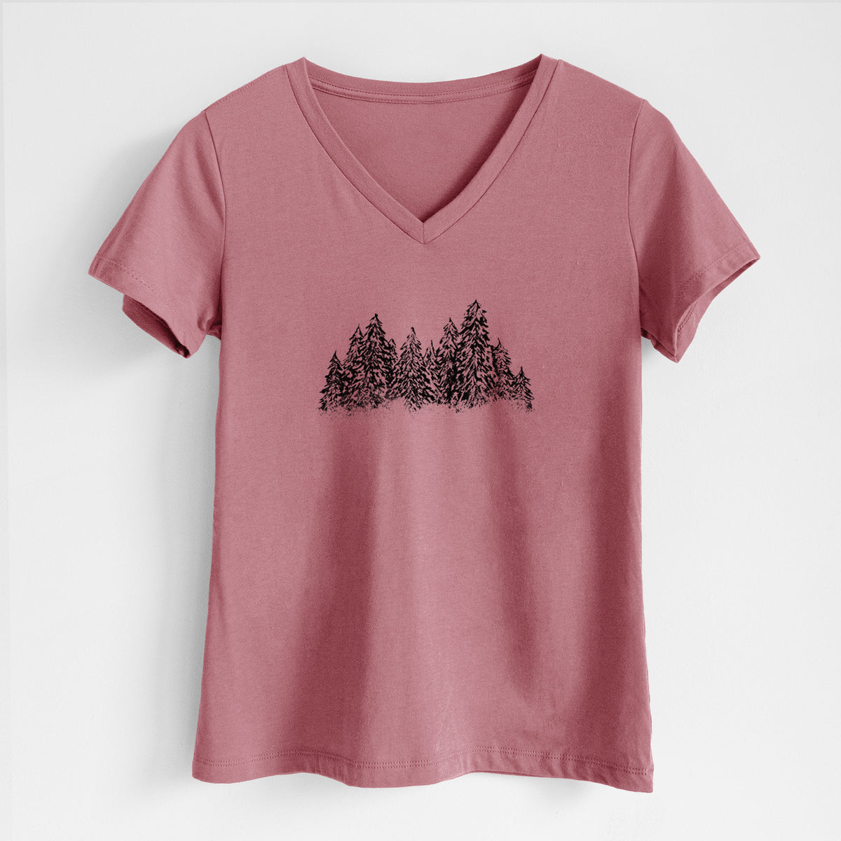 Mauve pink women's relaxed fit cotton V-neck t-shirt laid flat, printed with a black ink illustration of a row of snow-dusted evergreen trees.
