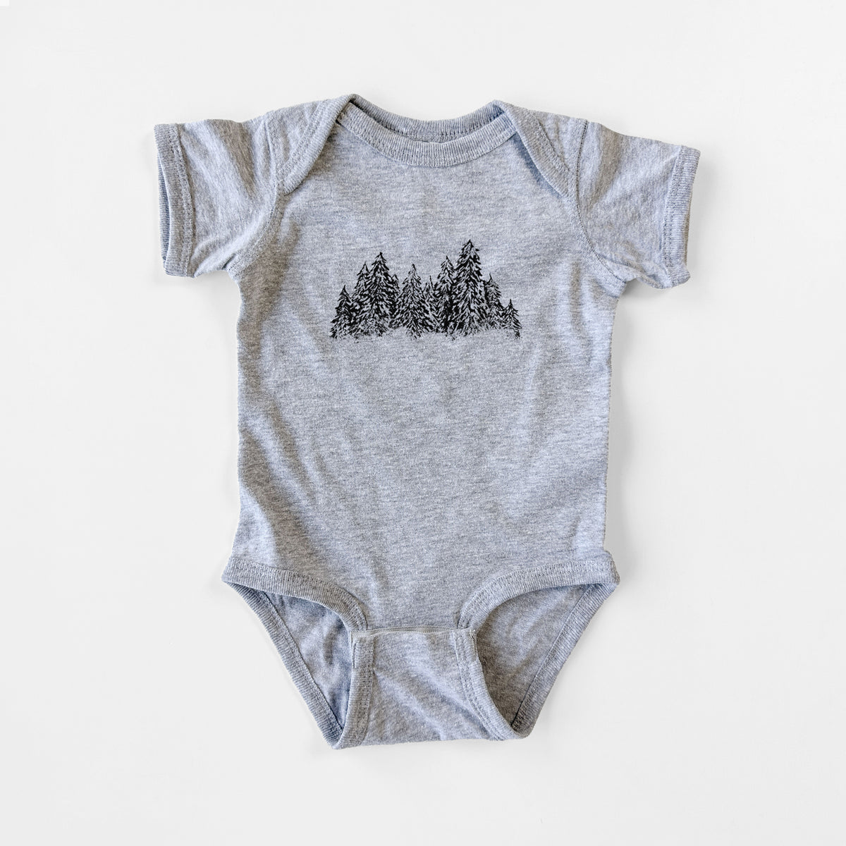 Grey baby bodysuit laid flat, printed with a black ink illustration of a row of snow-dusted evergreen trees.