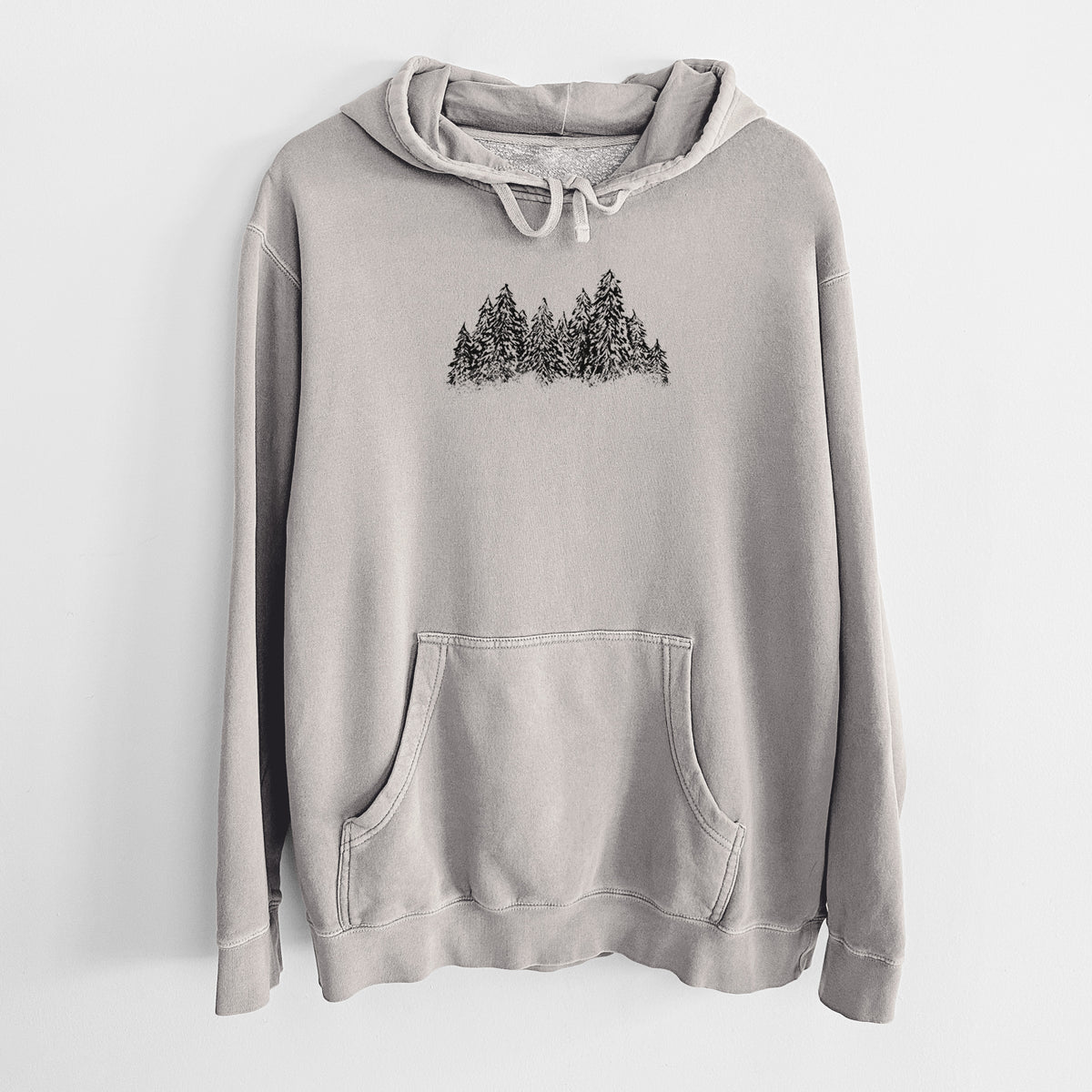 Cement grey pigment dyed hoodie laid flat, printed with a black ink illustration of a row of snow-dusted evergreen trees.