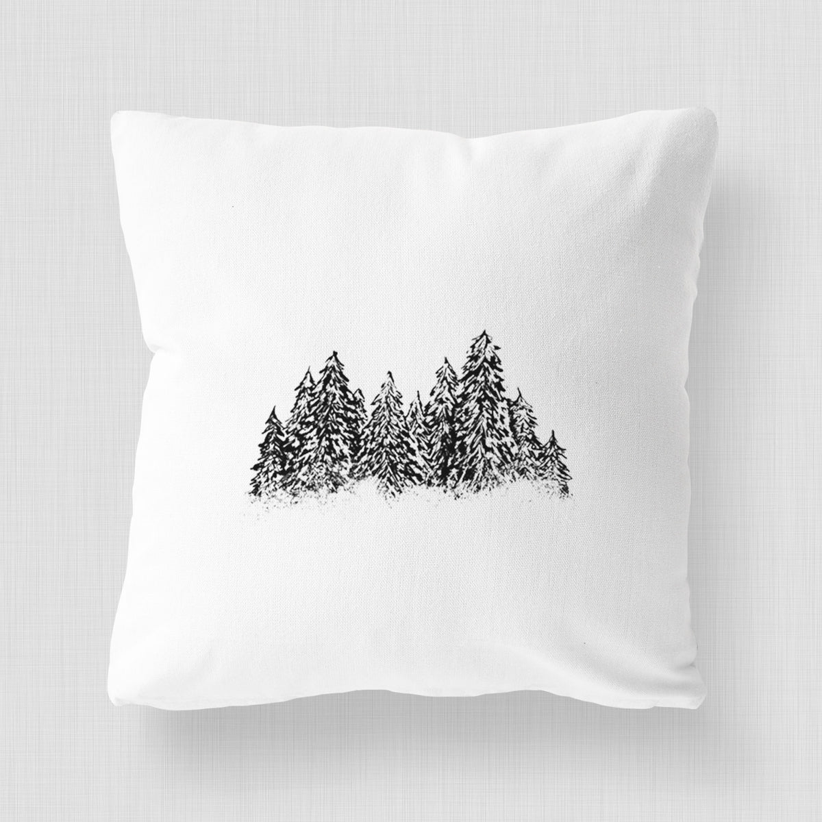 White pillow cover printed with a black ink illustration of a row of snow-dusted evergreen trees.