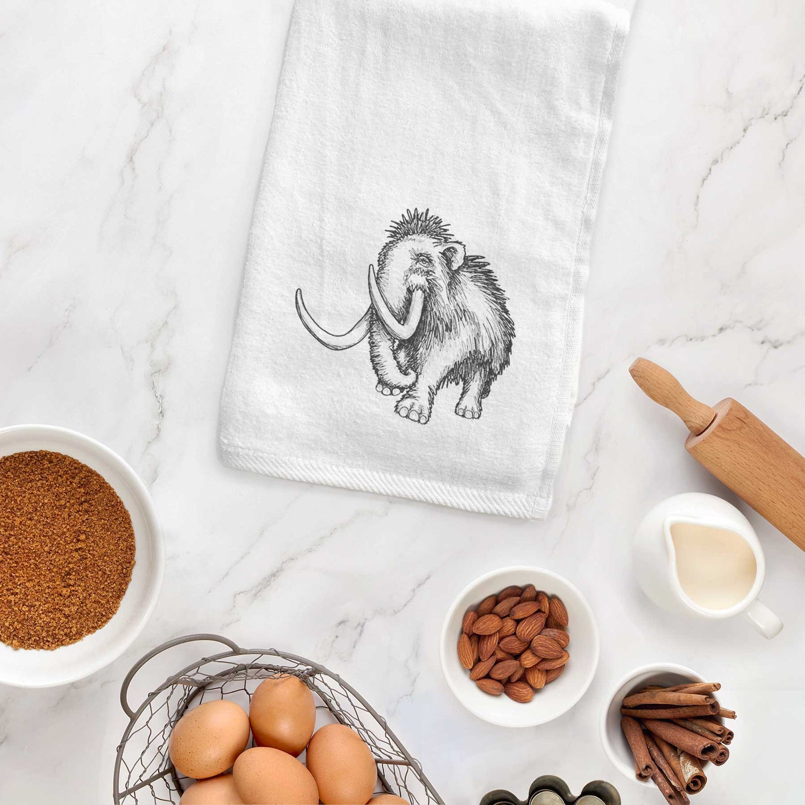 White hand towel printed with a black ink illustration of a woolly mammoth with long curved tusks.