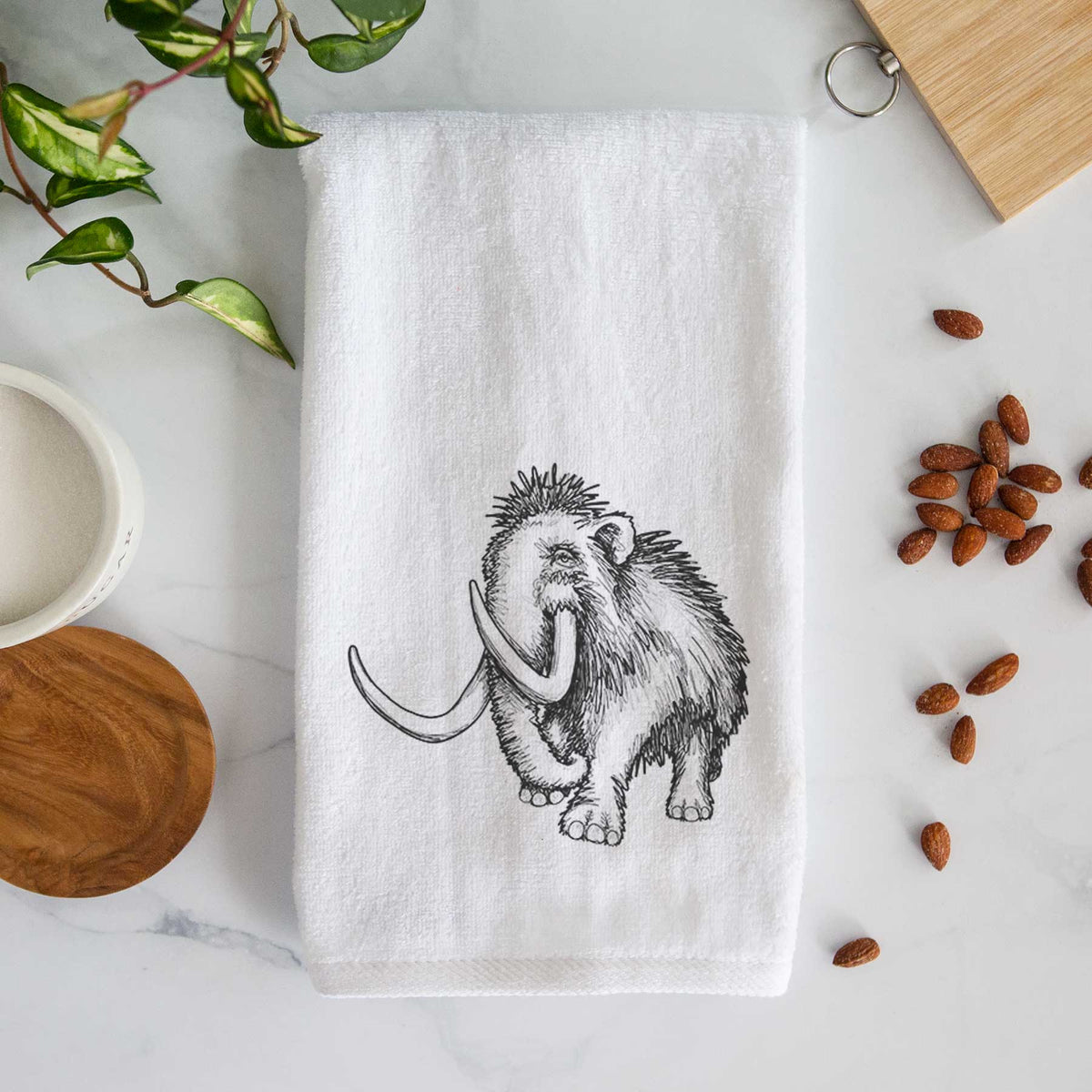 White hand towel printed with a black ink illustration of a woolly mammoth with long curved tusks.
